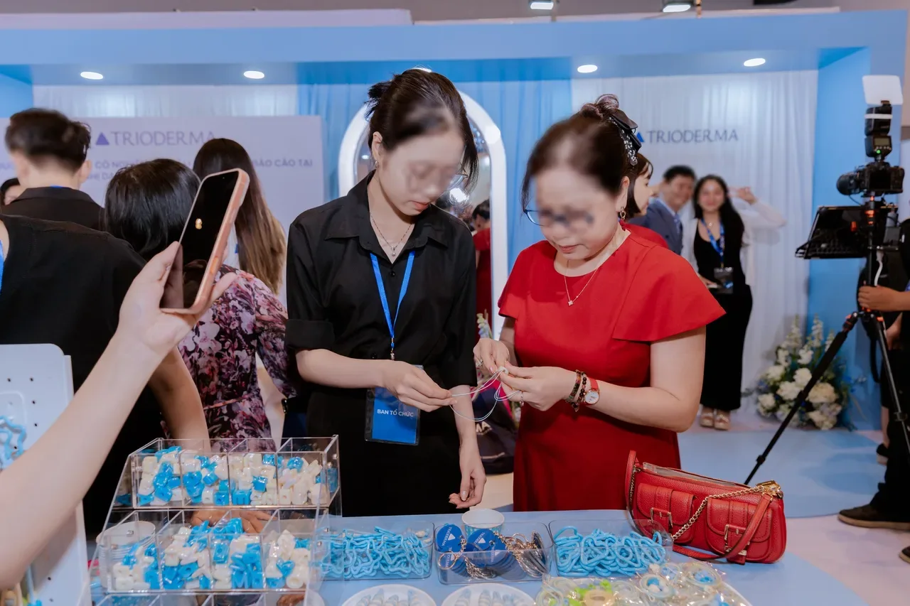 Khách tự xâu móc treo túi tại khu hoạt động của booth Trioderma trong hội nghị