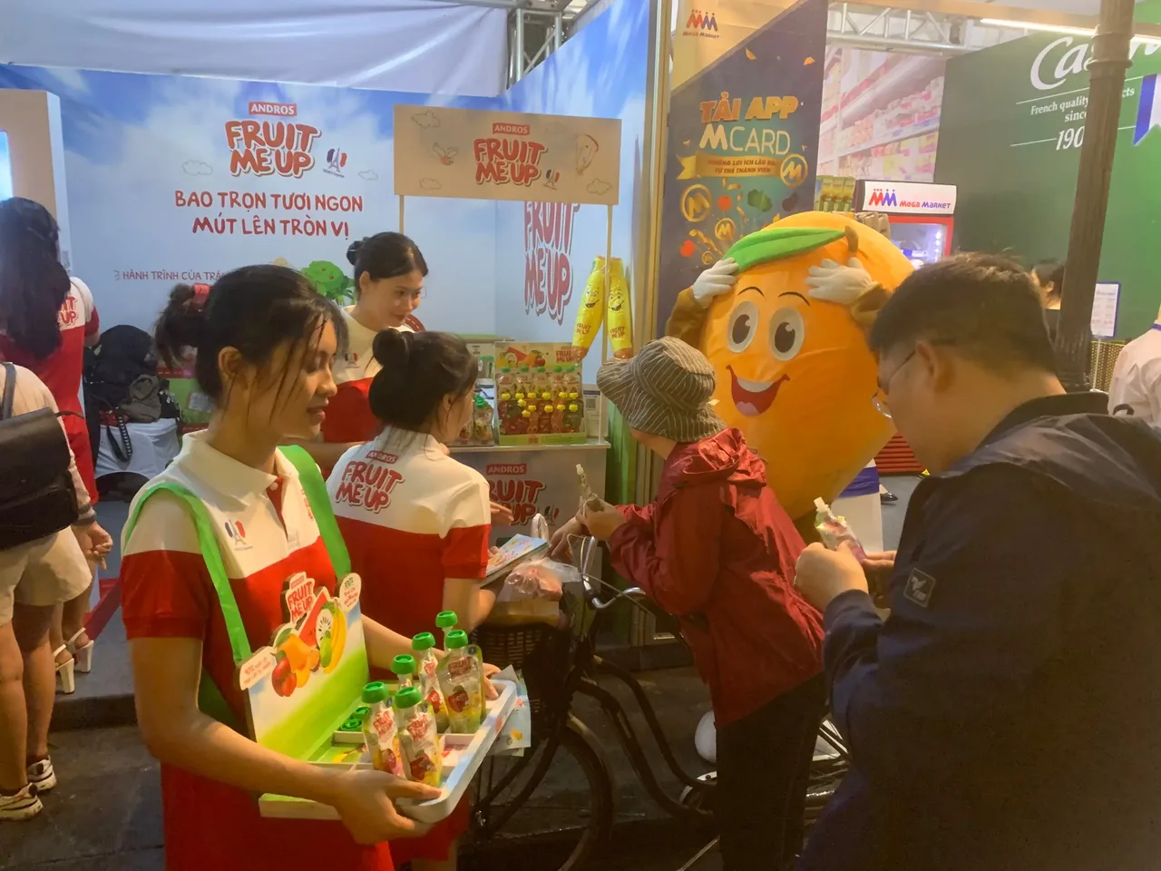 PG Fruit Me Up cầm khay sản phẩm mời khách cùng mascot tại French Food Festival Hà Nội