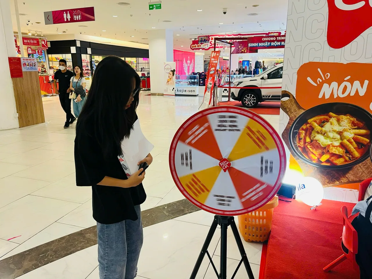 Vòng quay trò chơi đặt cạnh bảng giới thiệu cửa hàng BonChon tại Giga Mall