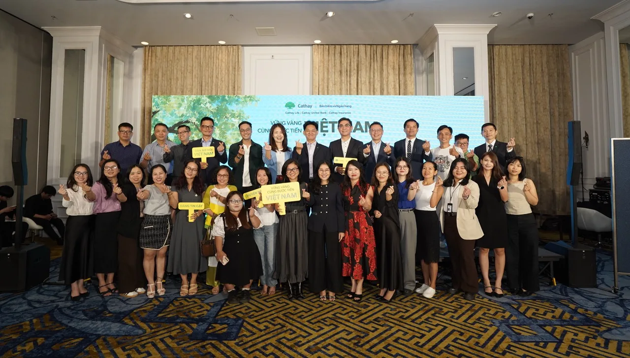 Khách mời báo chí và đội ngũ Cathay chụp ảnh tập thể trên sân khấu sảnh Saigon 2, cầm hand props Vững vàng cùng bước tiến Việt Nam