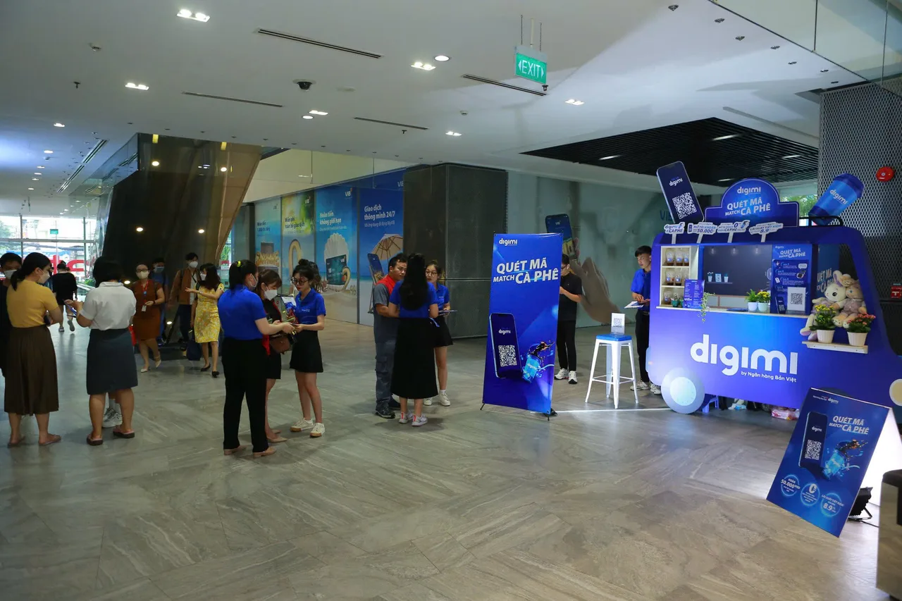 Coffee Tour DIGIMI: booth "Quét mã match cà phê" ở sảnh tòa nhà văn phòng, PG hướng dẫn nhân viên văn phòng mở app