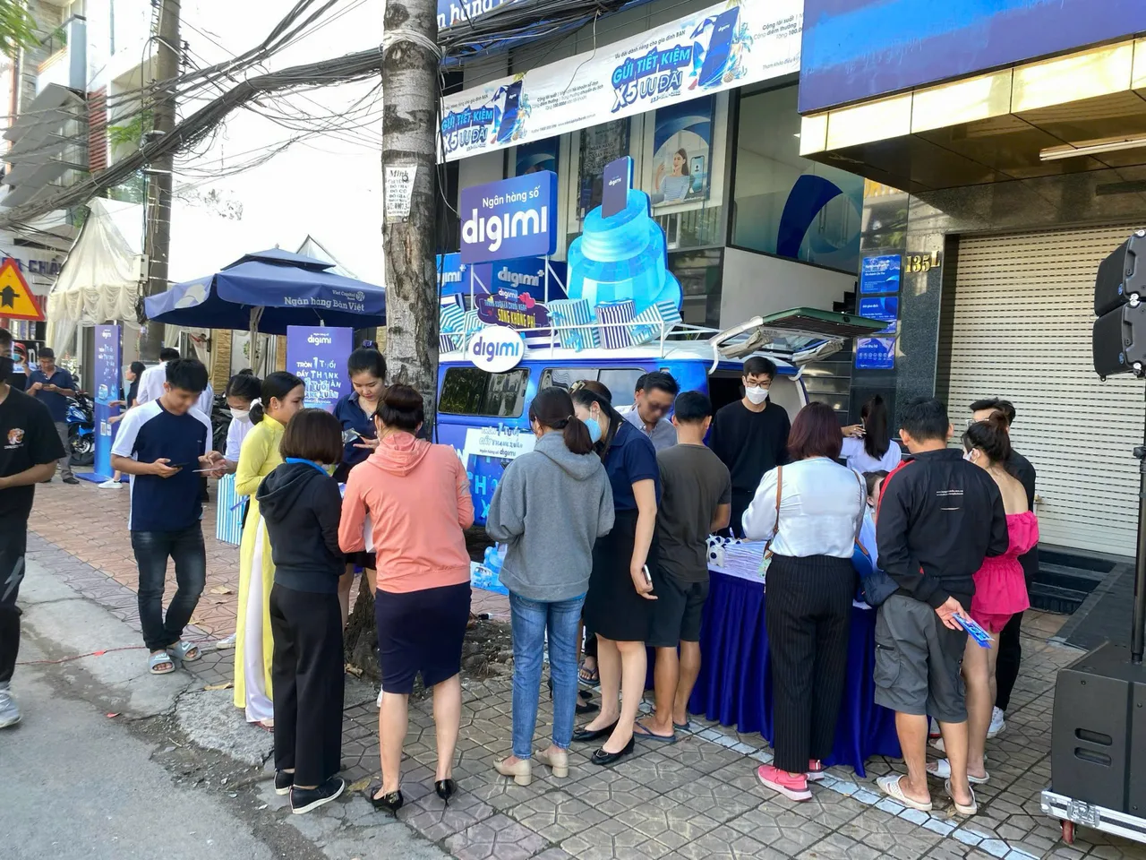 Khách vây quanh bàn tư vấn cạnh xe DIGIMI để mở app và nhận quà sinh nhật