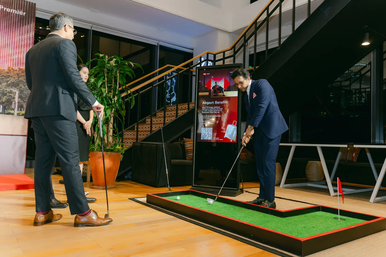 Khách thử khu golf mini có thảm cỏ và màn hình LCD đứng trong lúc chờ chương trình bắt đầu