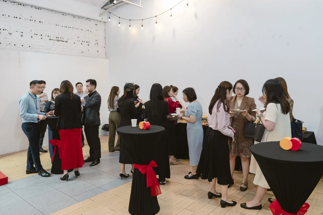 Khách giao lưu quanh bàn cocktail phủ khăn đen thắt nơ đỏ ở khu tea break tại Hà Nội