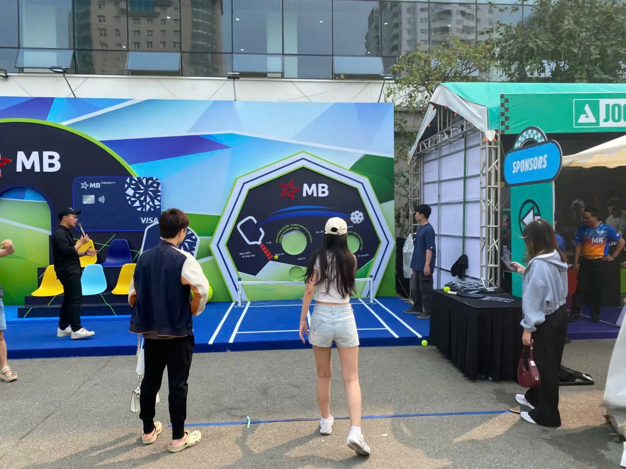 Người chơi đứng trước vách mini game có các ô tròn mục tiêu, người xem đứng chờ phía sau