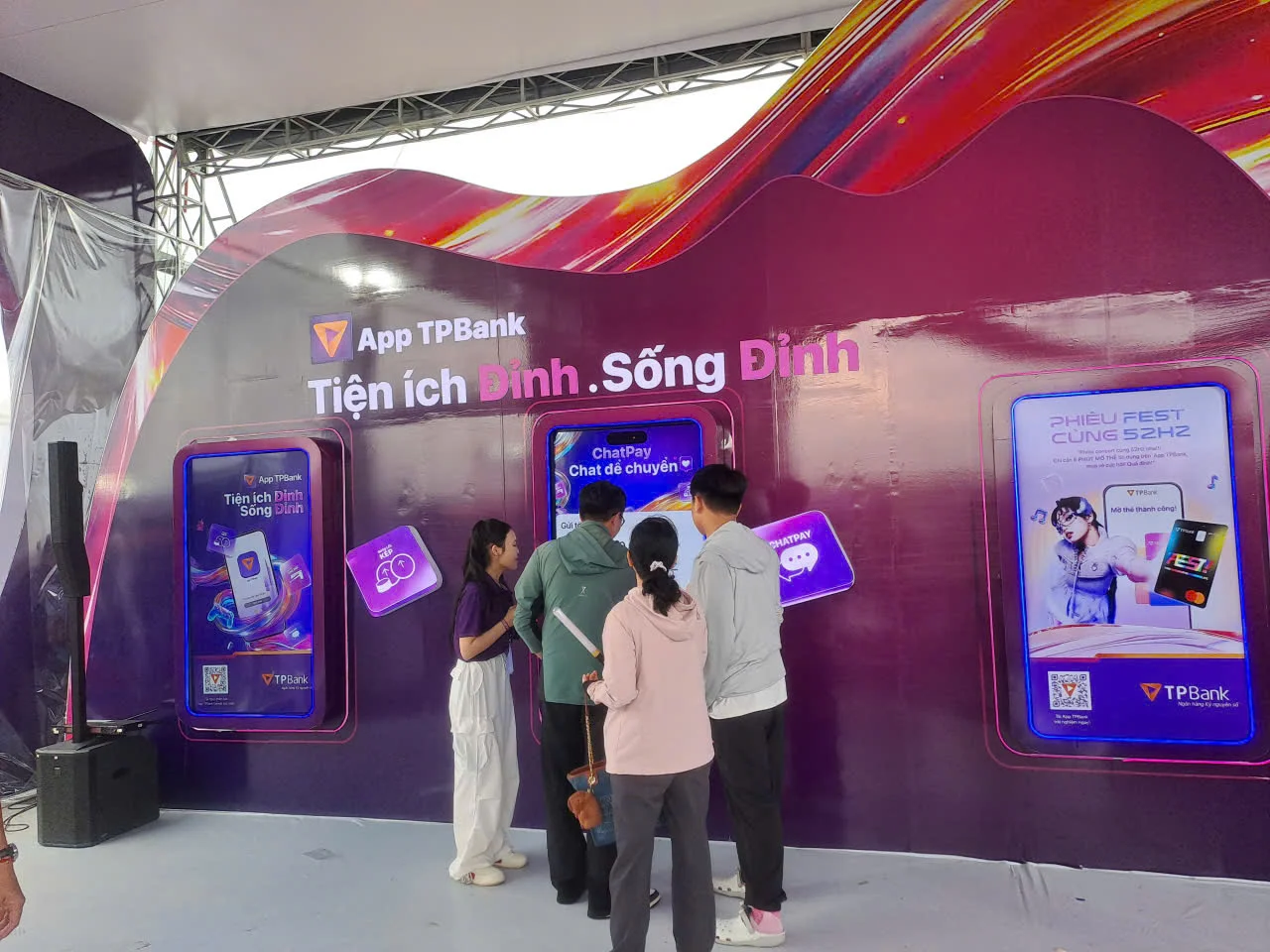 Đội promoter TPBank (đồng phục tím) với ô thương hiệu tiếp cận khán giả tại khu vực concert ngoài trời - trời mưa nhẹ